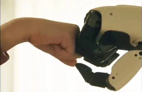 A close-up of the LG CLOiD robot's hand giving a fist bump to a human hand, symbolizing human-robot interaction.
