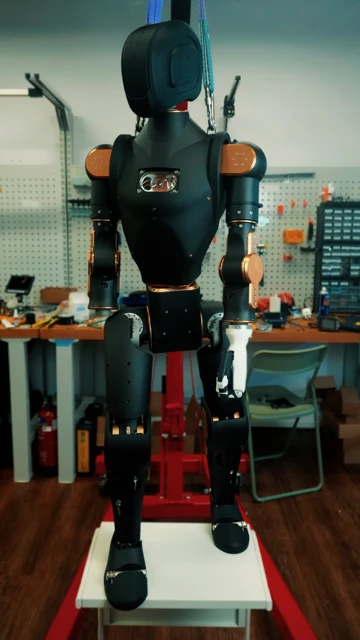 A majdnem teljesen összeszerelt Asimov humanoid robot egy műhelyben függesztve.