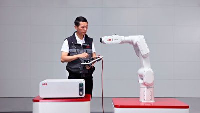 Egy mérnök egy ABB IRB 1200 robotkart programoz egy tabletes vezérlővel.